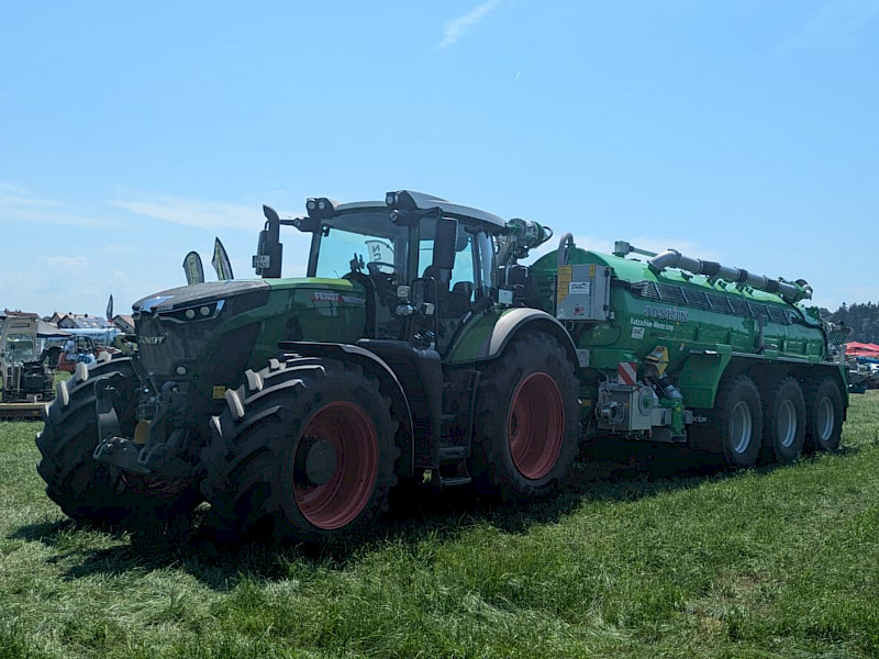 LKW, Transporter und ein paar Sonnenschirme auf einer Wiese. Feldtag 2024